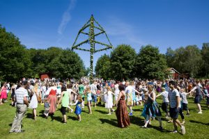 Åkersberga, Sweden - June, 22th 2012: People standing around the Midsummer Pole in Åkersberga, Sweden. Midsummer Celebration is a traditional celebration for the summer solstice. Since the 1950s, for practical reasons, people celebrate Midsummer on Midsummer Eve, which is always on a Friday between June 19 and June 25